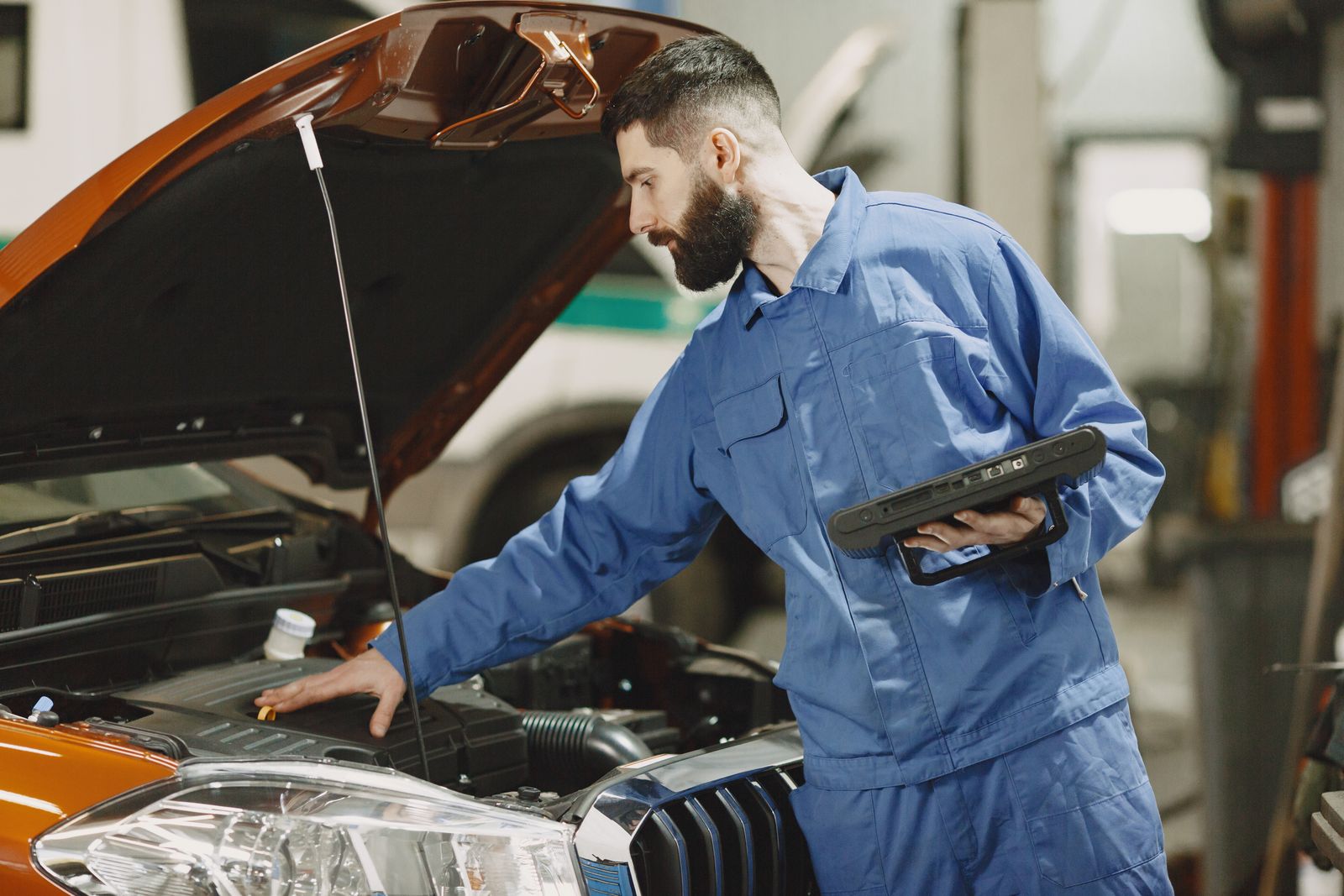 Mécanicien penché sur un moteur avec une tablette de diagnostic